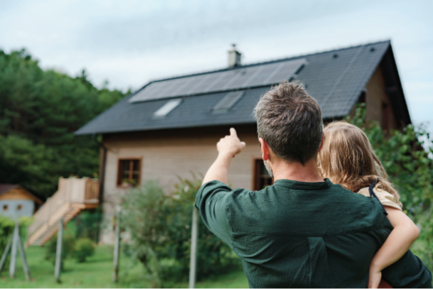 Familie steht vor ihrem Haus. Der Vater zeigt auf die Sorlarthermieinstallation auf dem Dach